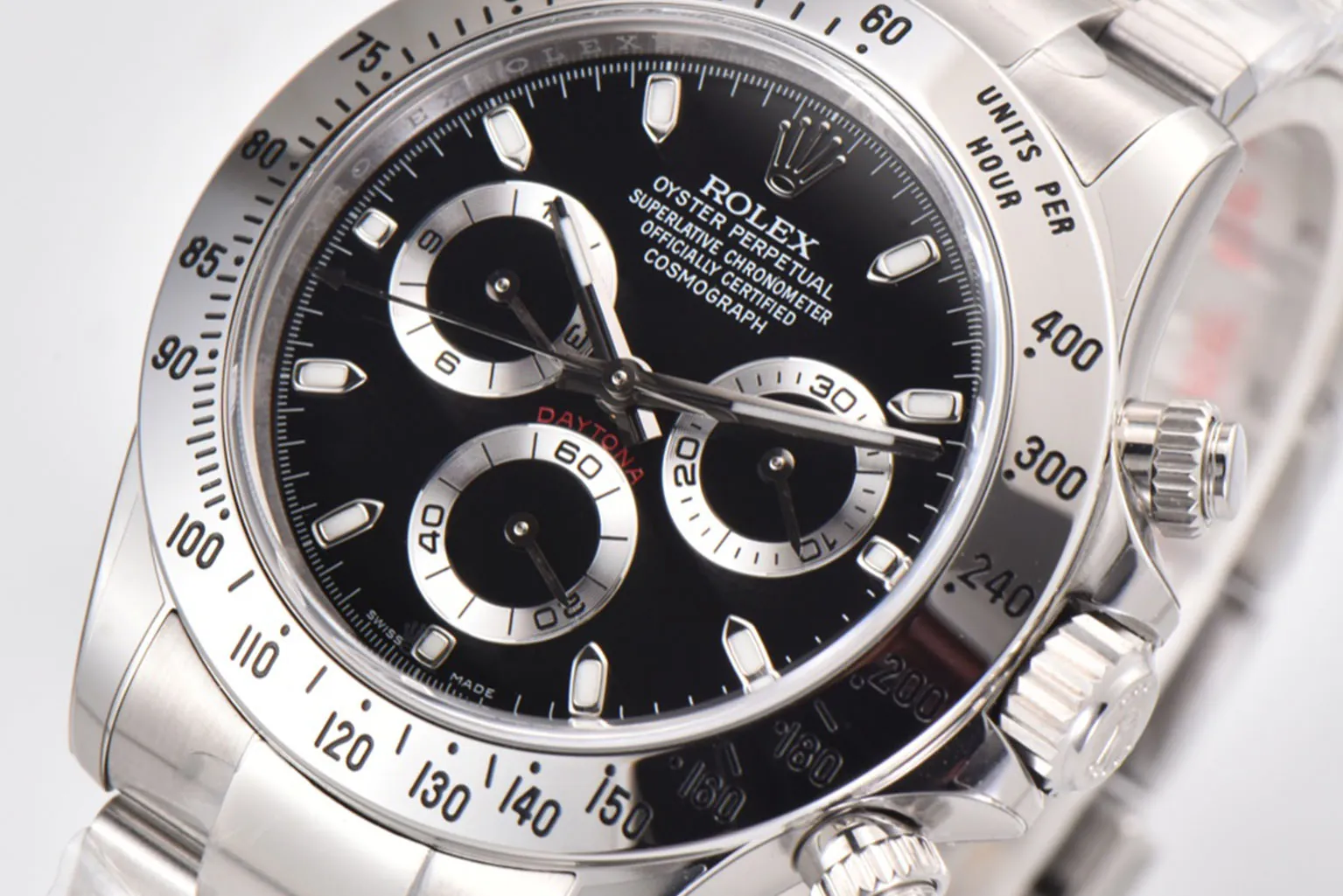 Macro close-up of a Rolex Daytona chronograph dial featuring a black face, contrasting silver subdials, engraved tachymeter bezel, polished hour markers, and precision stainless steel craftsmanship.